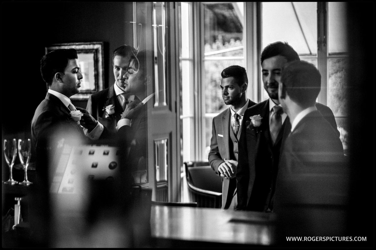 Documentary wedding photographer captures reflections of groomsmen in the bar before a wedding ceremony