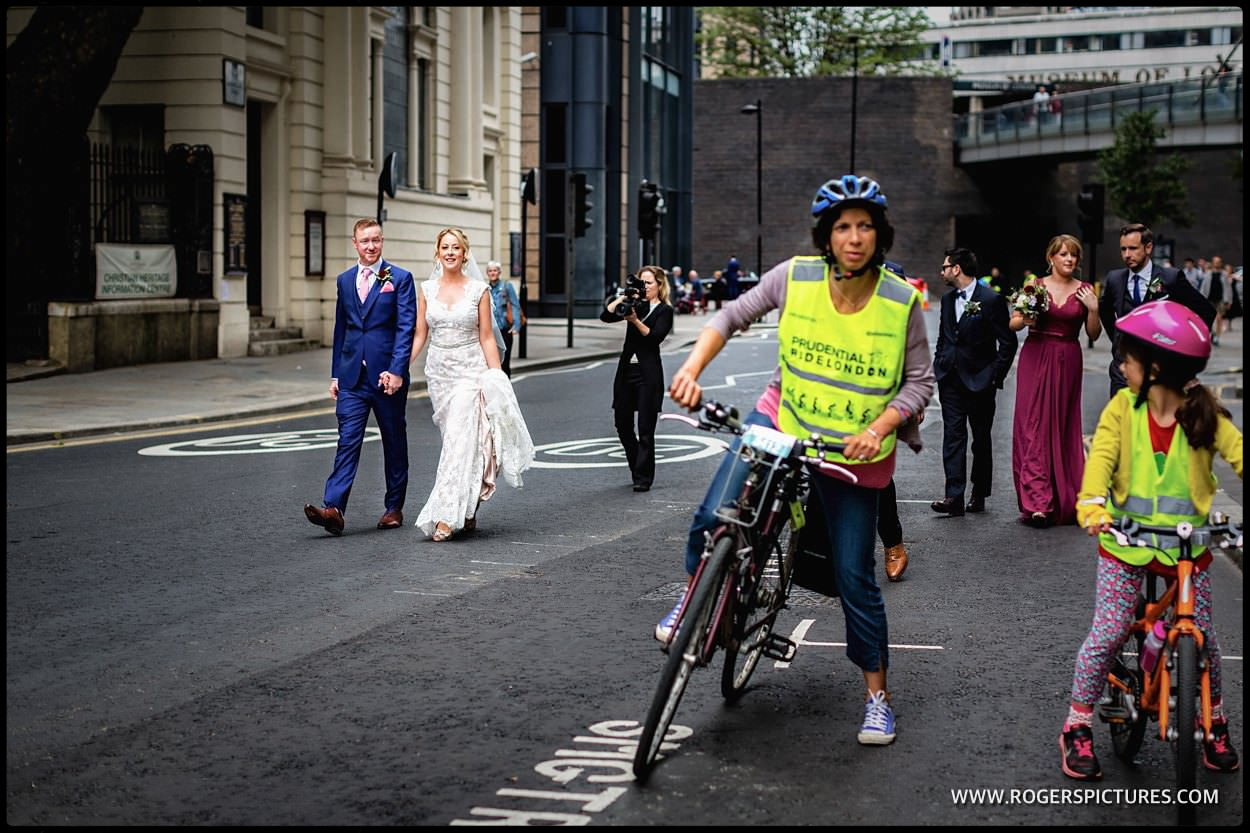 Bride and groom walk through London with cyclists