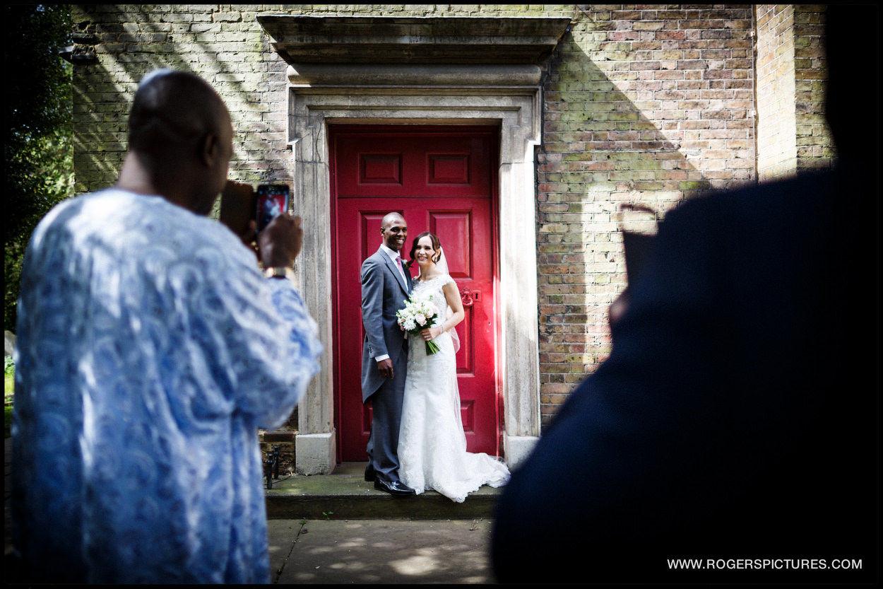 Portrait of bride and groom by a red door