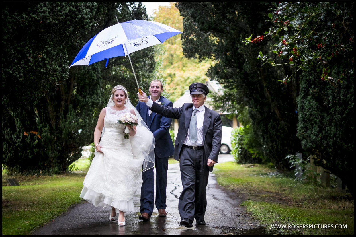 Bride with umbrella walking to Church