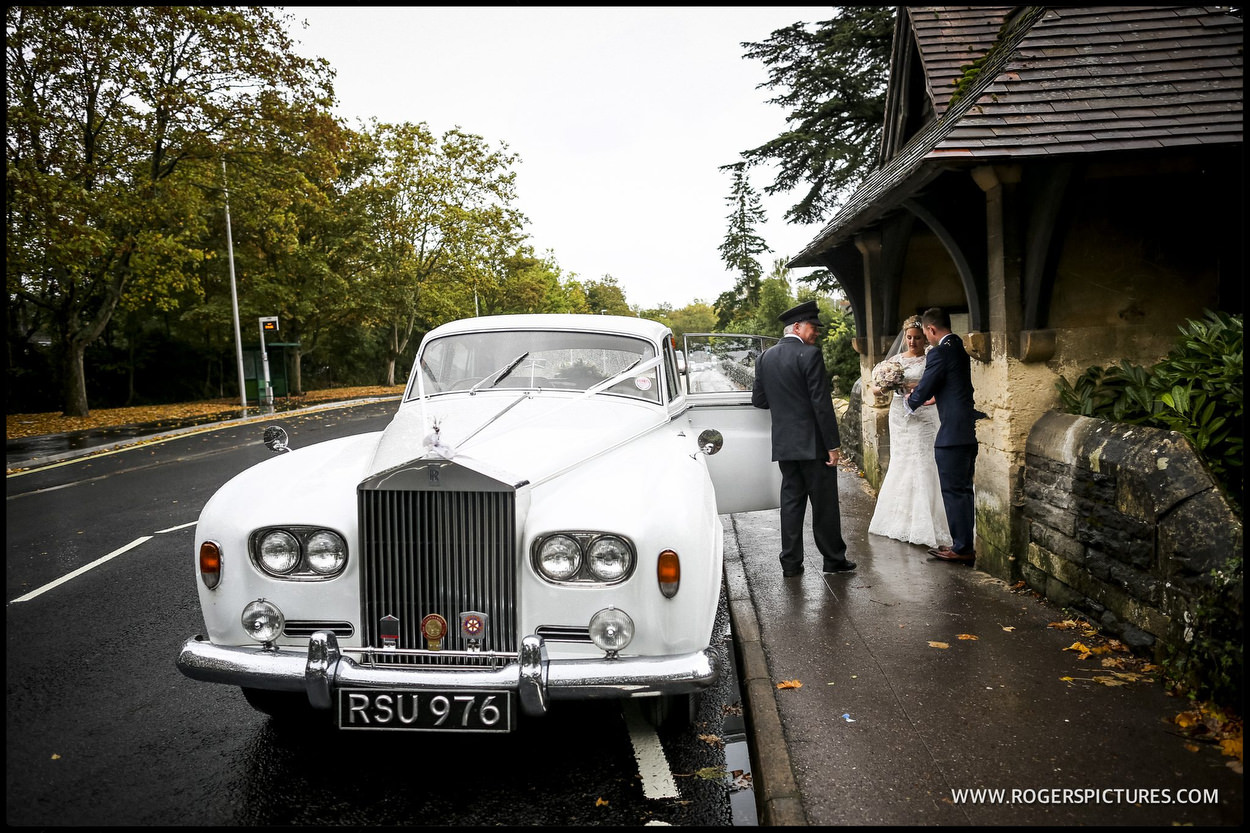 Bride and groom get into a Rolls-Royce wedding car