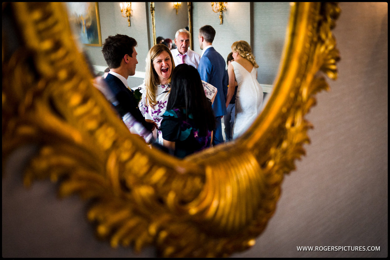 Reflection in oval mirror of wedding guests at a meal