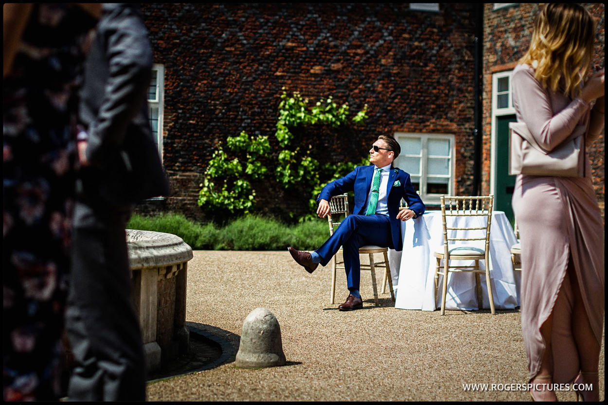 Wedding guest in A blue suit enjoys the sun in the courtyard