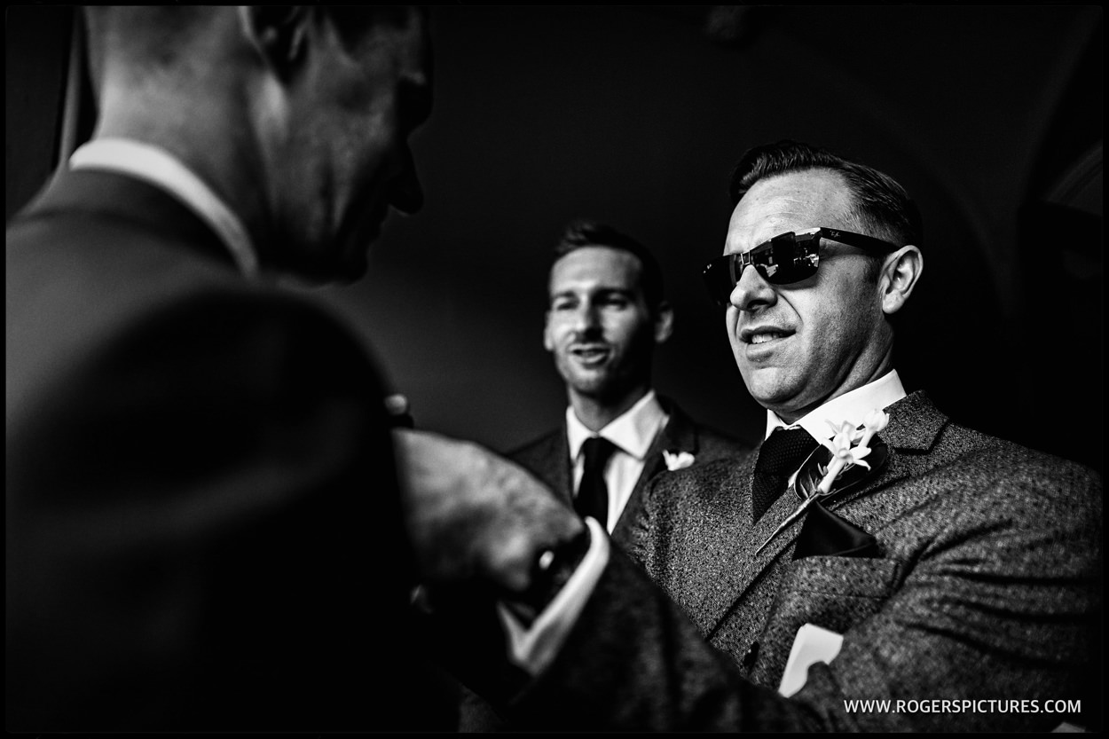 Man in sunglasses adjusts buttonhole