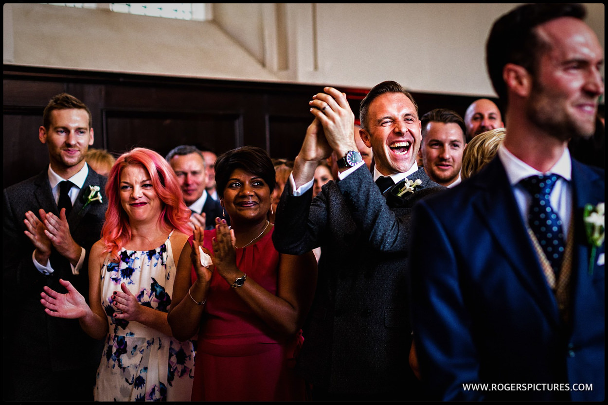 Laughing guests applaud after same-sex wedding ceremony