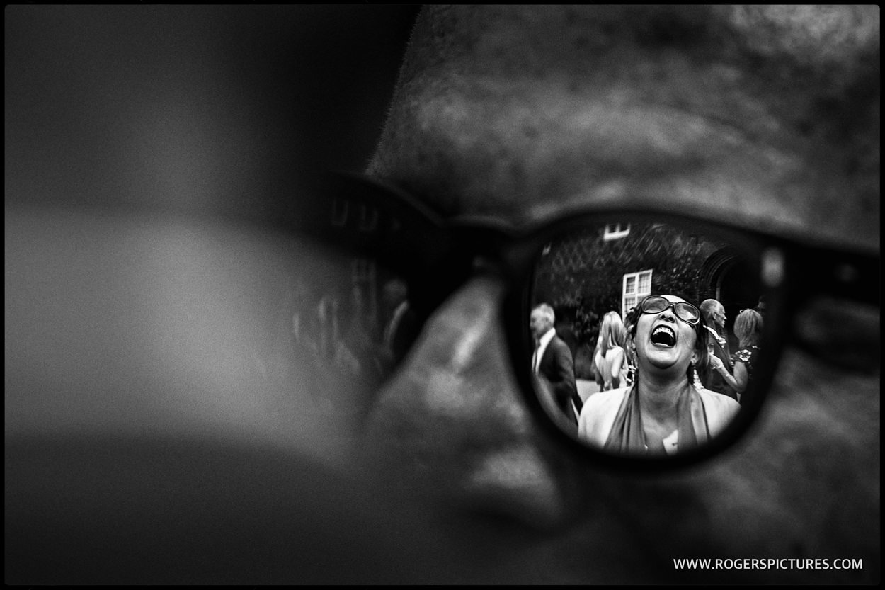 Reflection and sunglasses of laughing guest at Fulham Palace wedding