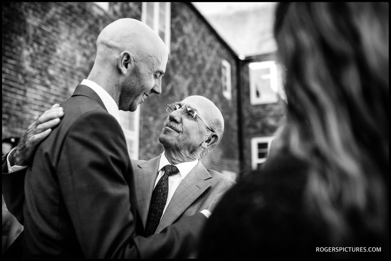 Groom and father hug at Fulham Palace wedding in London