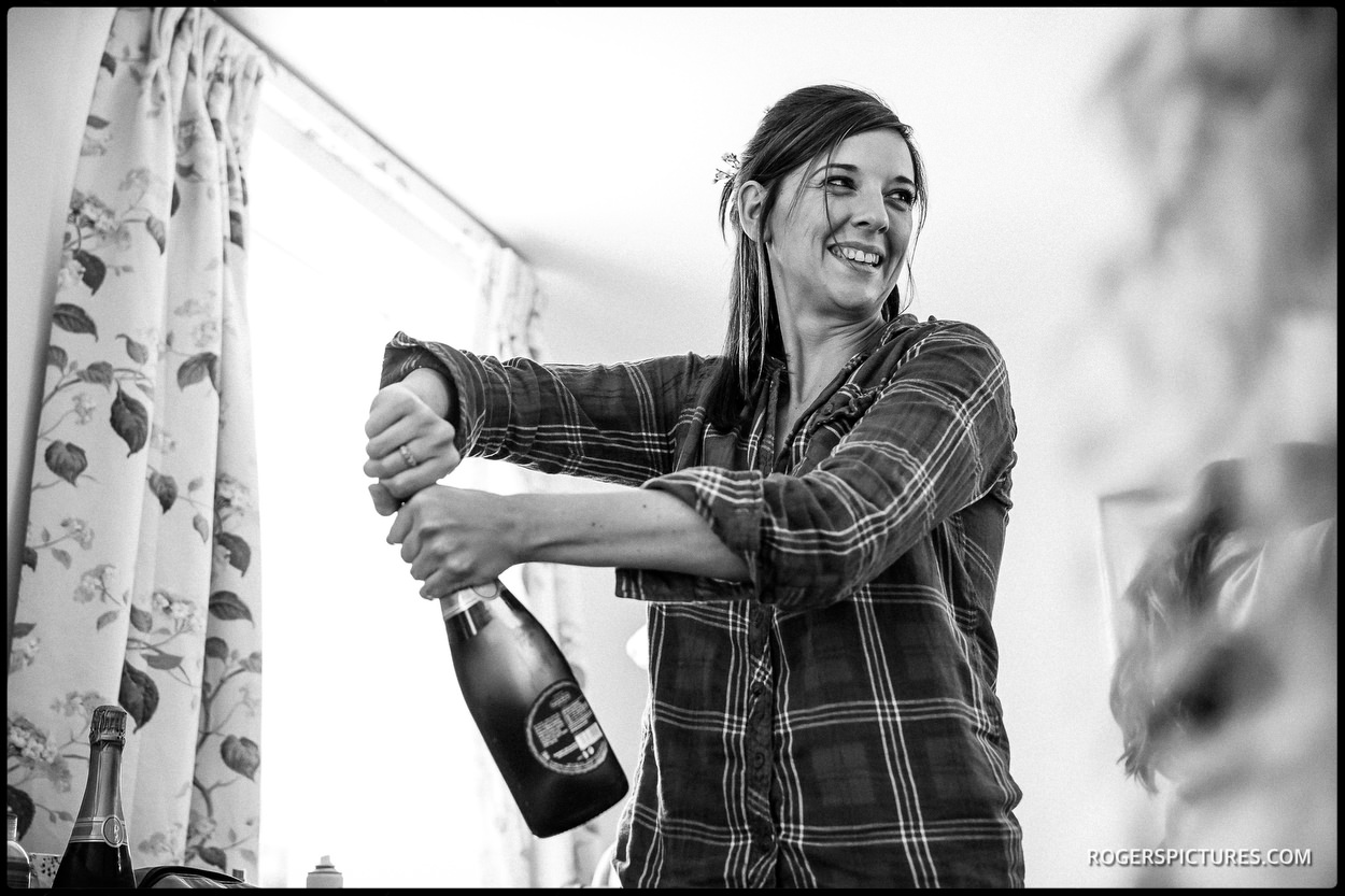 Bridesmaid opens champagne