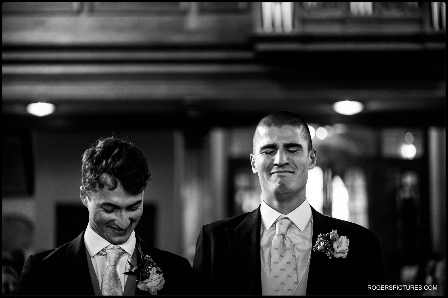 Black and white documentary photo pf an emotional looking groom in church before Bride arrives