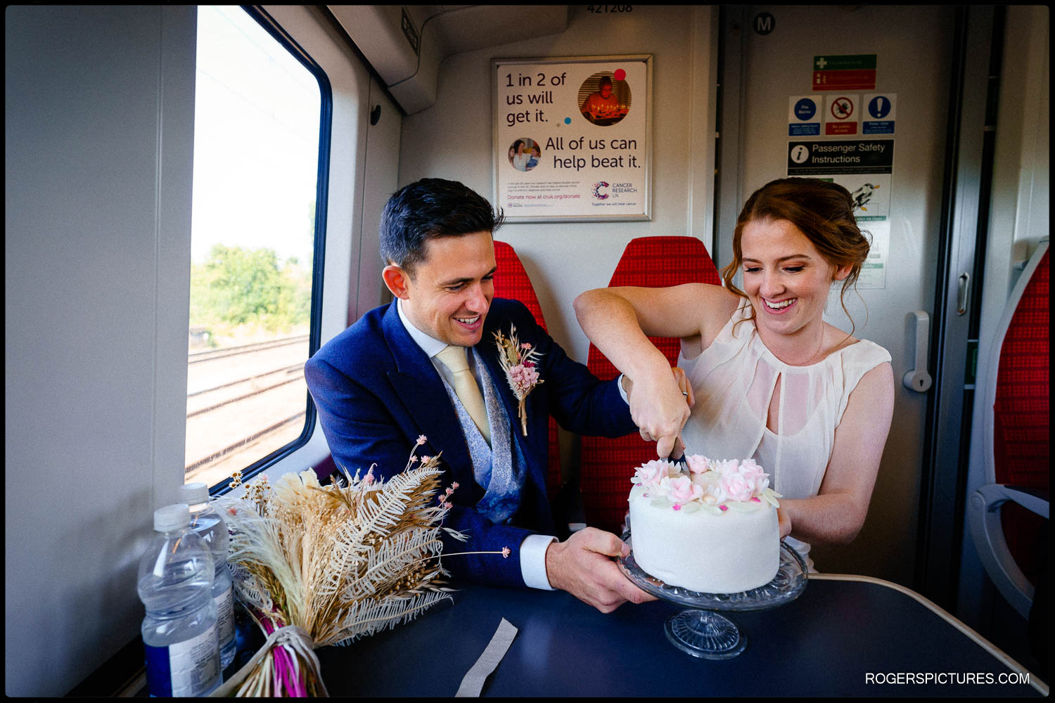 Unusual wedding photo of couple cutting their wedding cake on a train