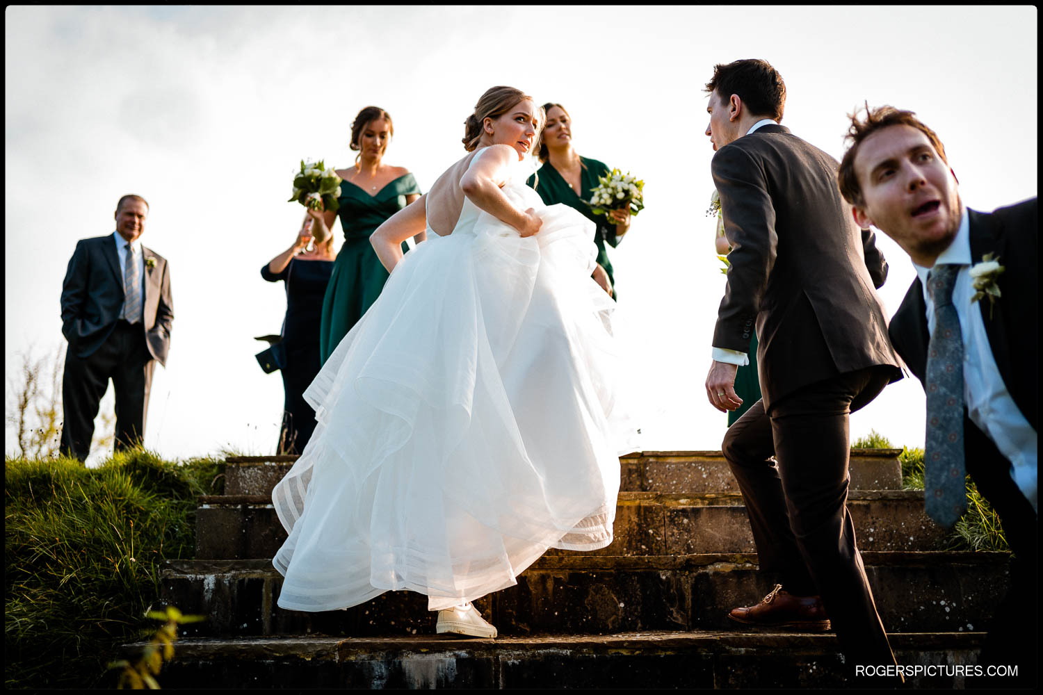 Bride climbing steps at outdoor English wedding