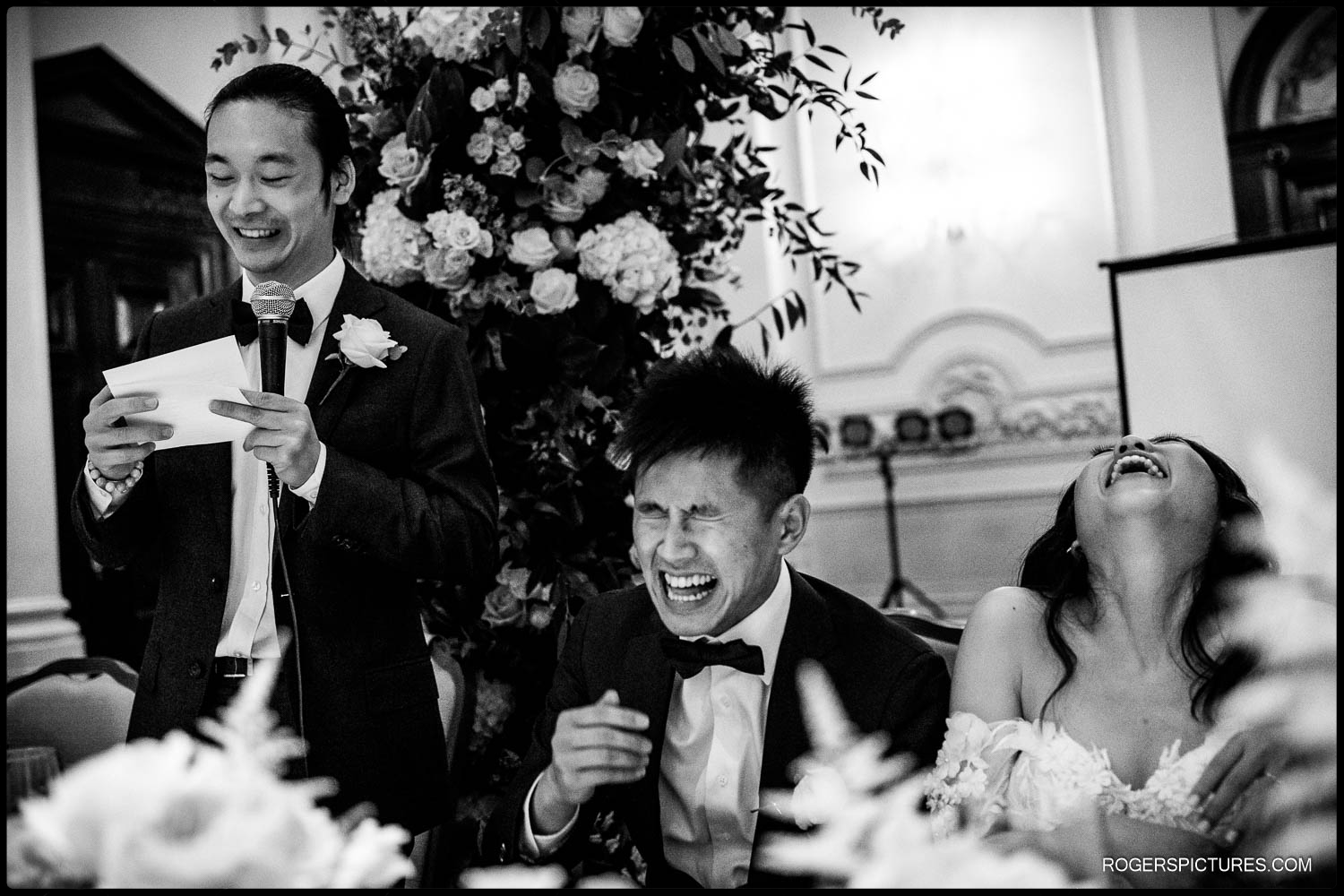 Bride and groom laugh during the best man's wedding speech at a London hotel