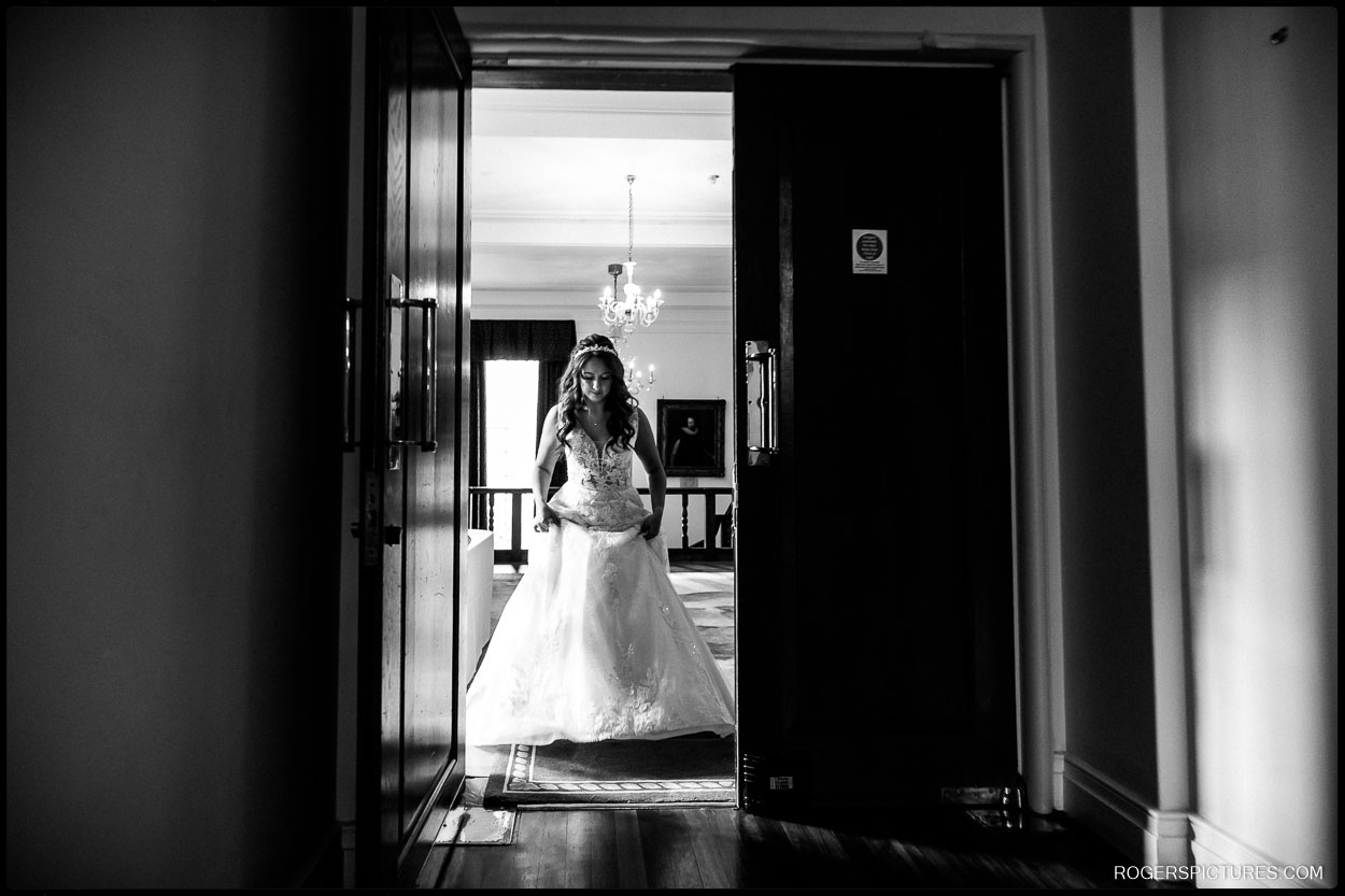 Bride Walking to Ceremony – A dramatic black and white shot of the bride walking alone through a dimly lit hallway, moments before the ceremony.