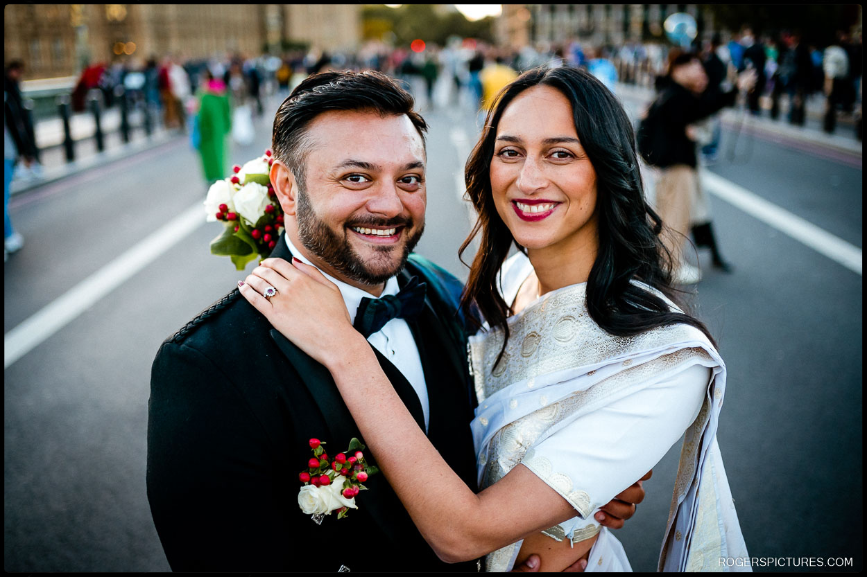 Smiling bride and groom embrace on Westminster Bridge, celebrating their Short London Wedding at Hendon Town Hall.