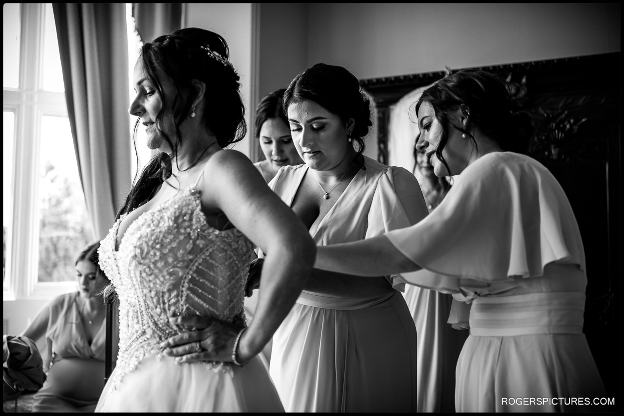 Black and white documentary wedding photograph of bride getting ready