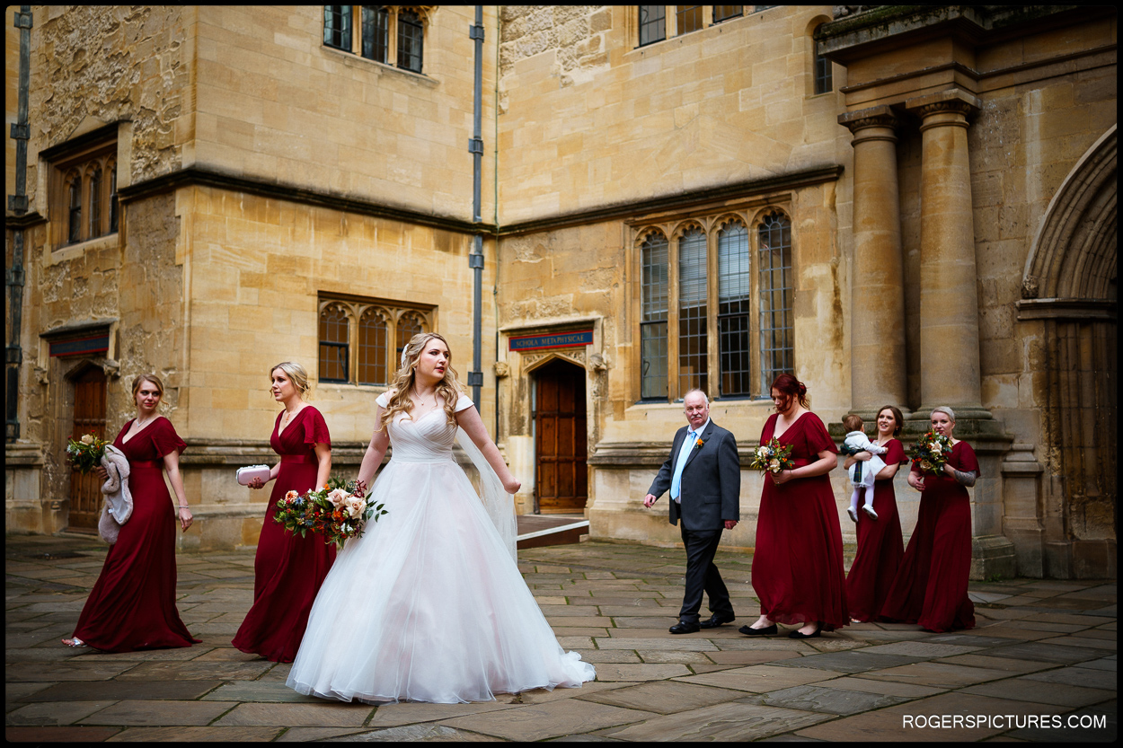 Bride and bridesmaids walk across the courtyard at Bodleian libraries in Oxford