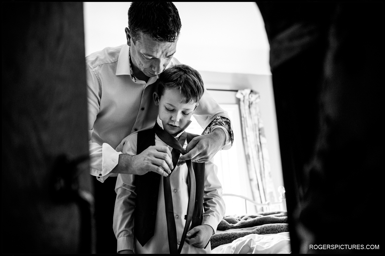 Father helping son with a tie before a church wedding in Sussex