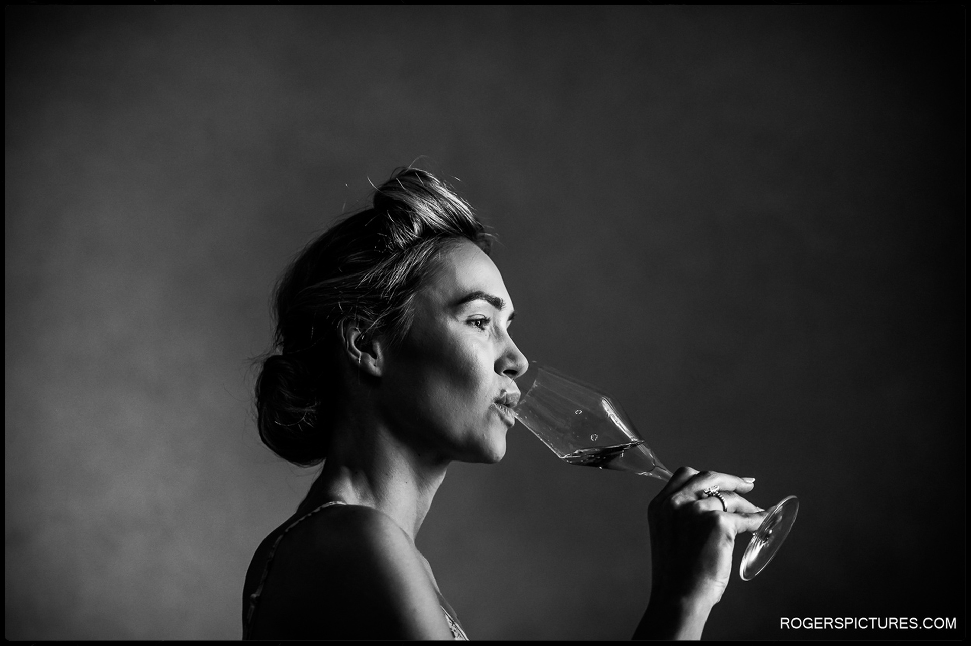 A bride in soft lighting sips champagne in an elegant black-and-white portrait before her Woodland Wedding in Tuscany.