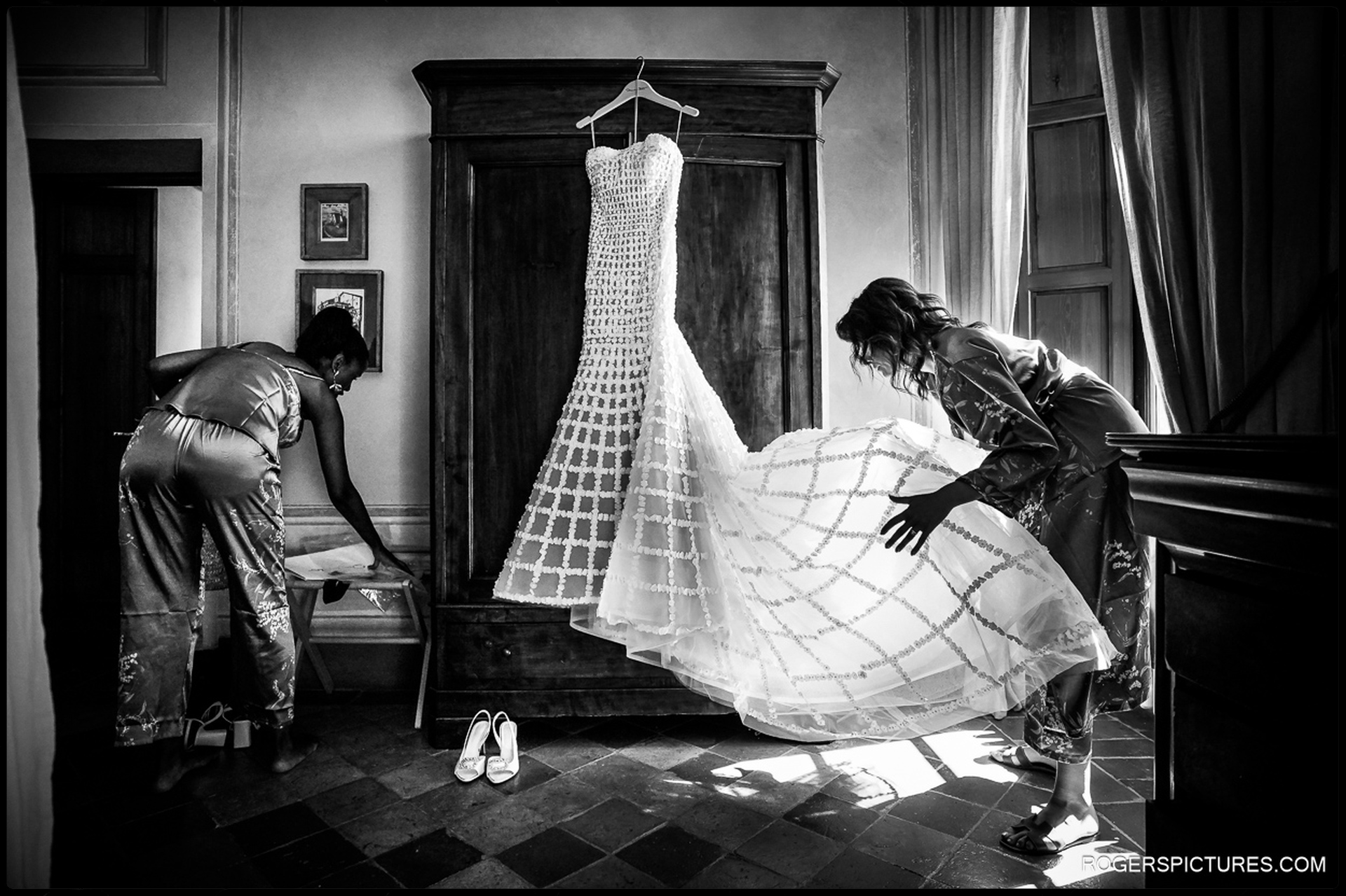 Bridesmaids carefully arrange a stunning wedding dress, preparing for Felicia and Kunal's Woodland Wedding in Tuscany at Borgo Pignano.