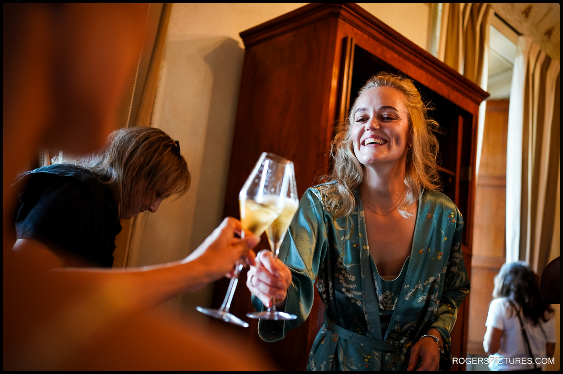 A joyful bridesmaid toasts with champagne during the lively preparations for a Woodland Wedding in Tuscany.