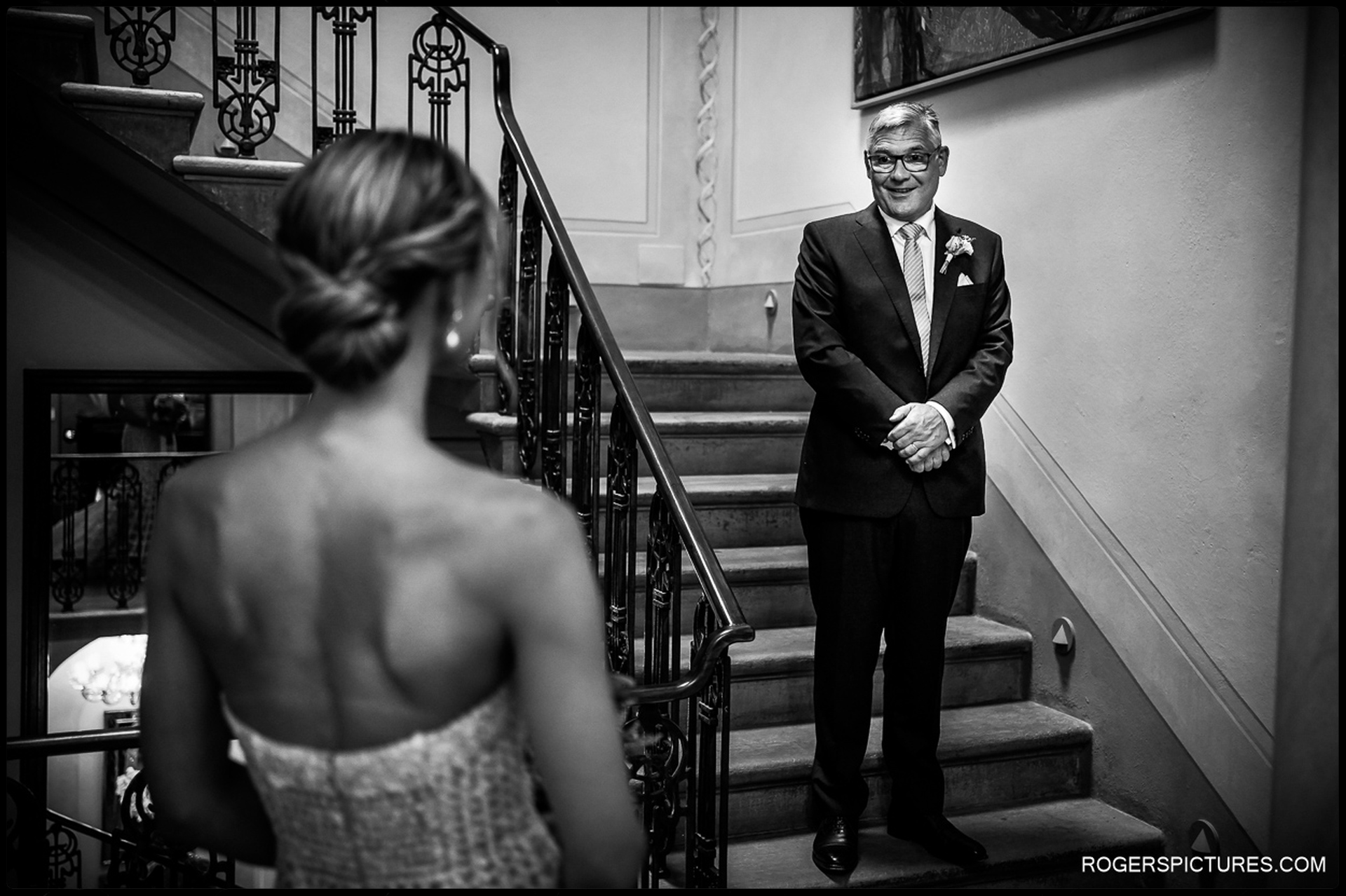 Bride's First Look with Father – A touching black and white moment as the bride's father sees her in her wedding dress for the first time on a grand staircase.