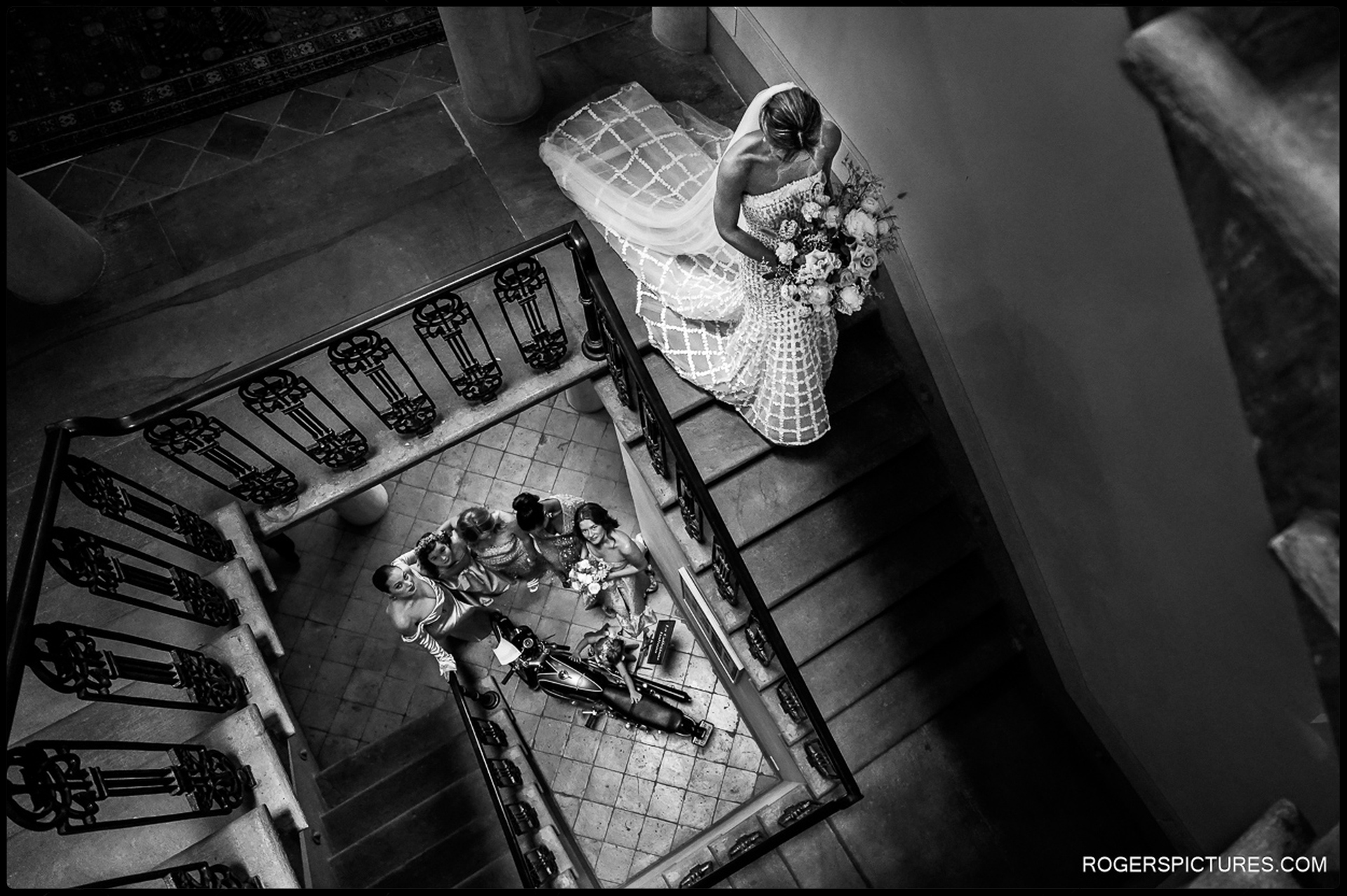 Woodland Wedding in Tuscany Bride Descending the Staircase – A dramatic overhead shot of the bride walking down the staircase, her bridal party watching in admiration.