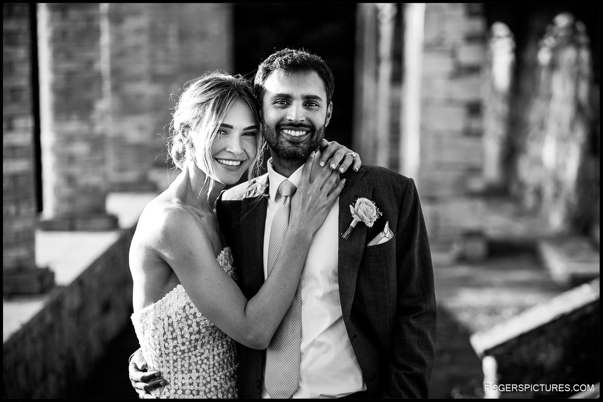 Bride and groom embrace near historic stone ruins during their wedding in Tuscany.