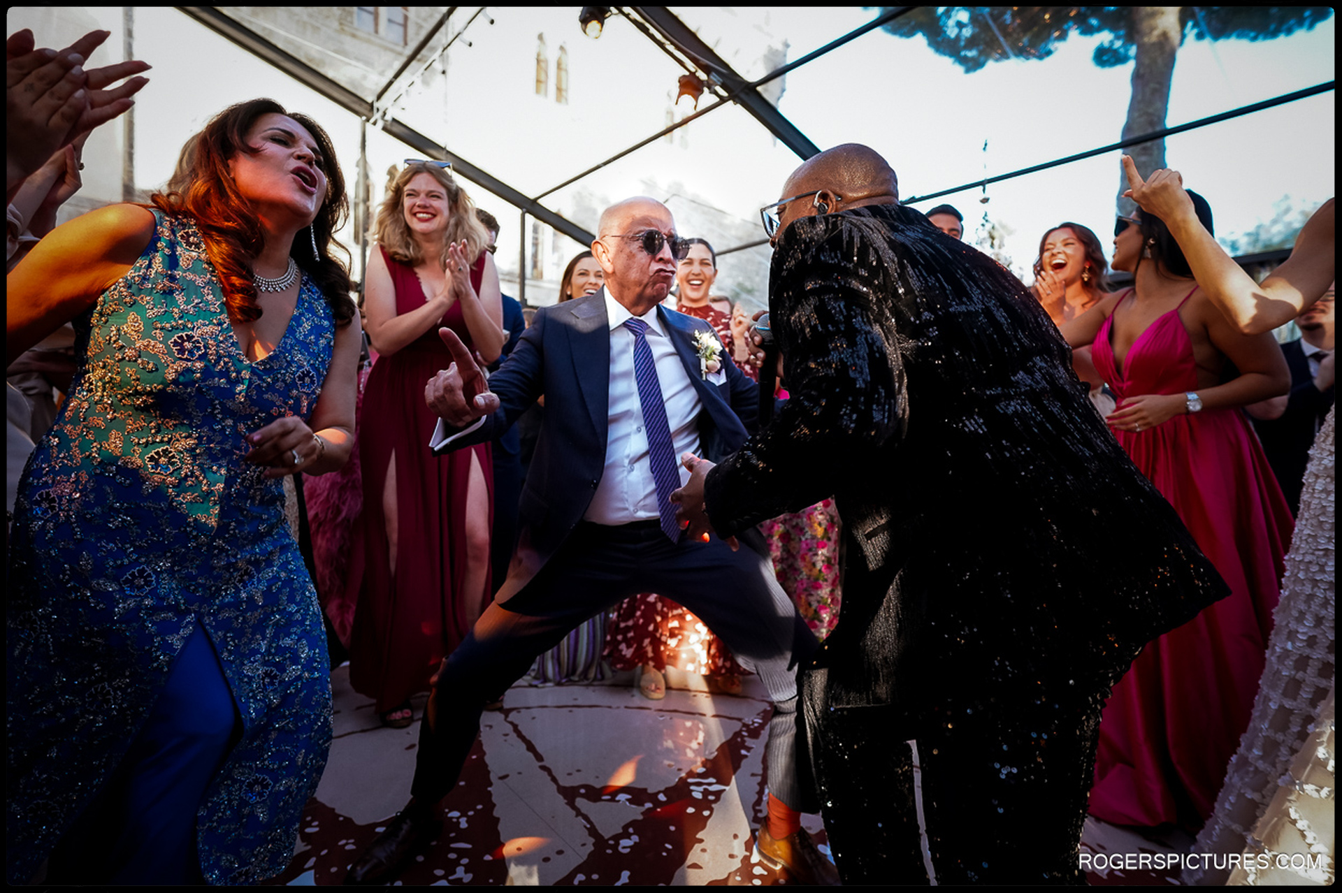 Guests cheer as a father-of-the-bride dances enthusiastically with the wedding singer.