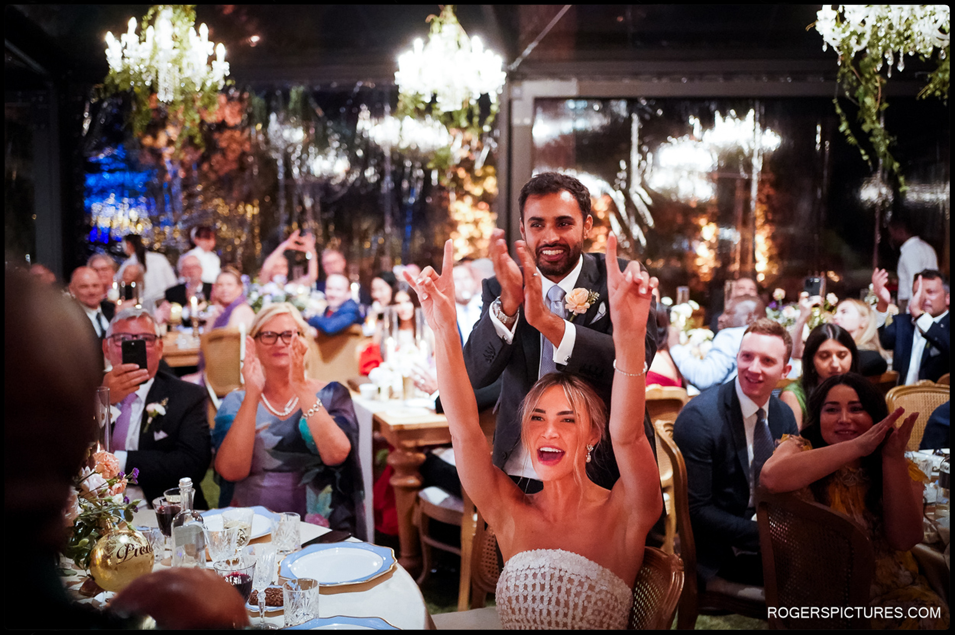 The bride and groom celebrate joyfully during a toast at their Tuscany wedding reception.