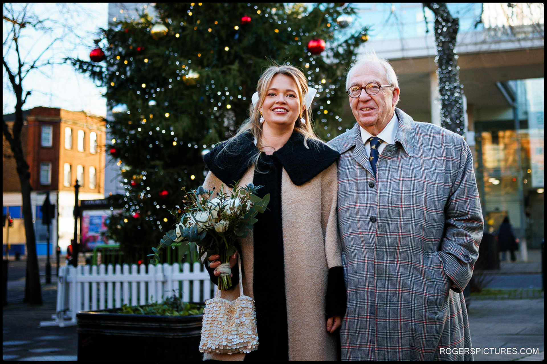 Bride and her father standing in front of a Christmas tree before the Short Wedding at Hackney Town Hall.
