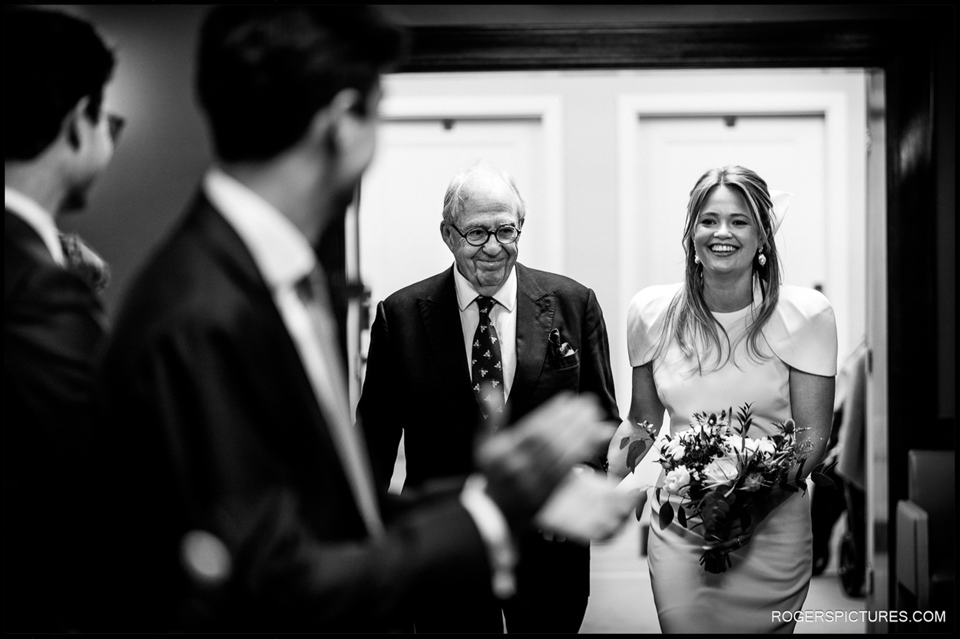 Bride and her father walking down the aisle, greeted by smiles at their Short Wedding at Hackney Town Hall.