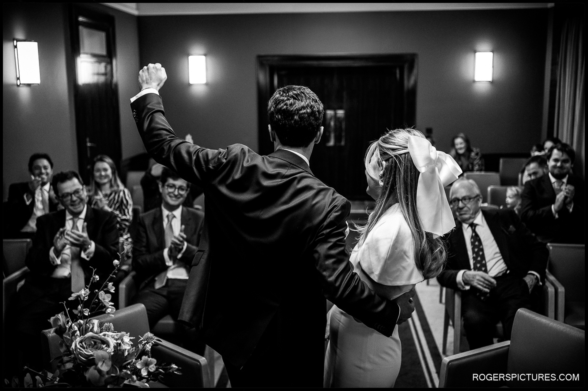 Newlyweds celebrate with raised hands as guests cheer at their Short Wedding at Hackney Town Hall.