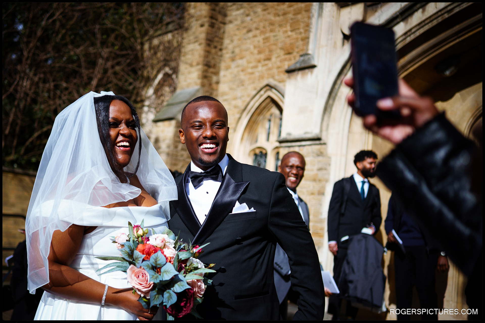 Bride and groom smiling for photos outside church after their ceremony