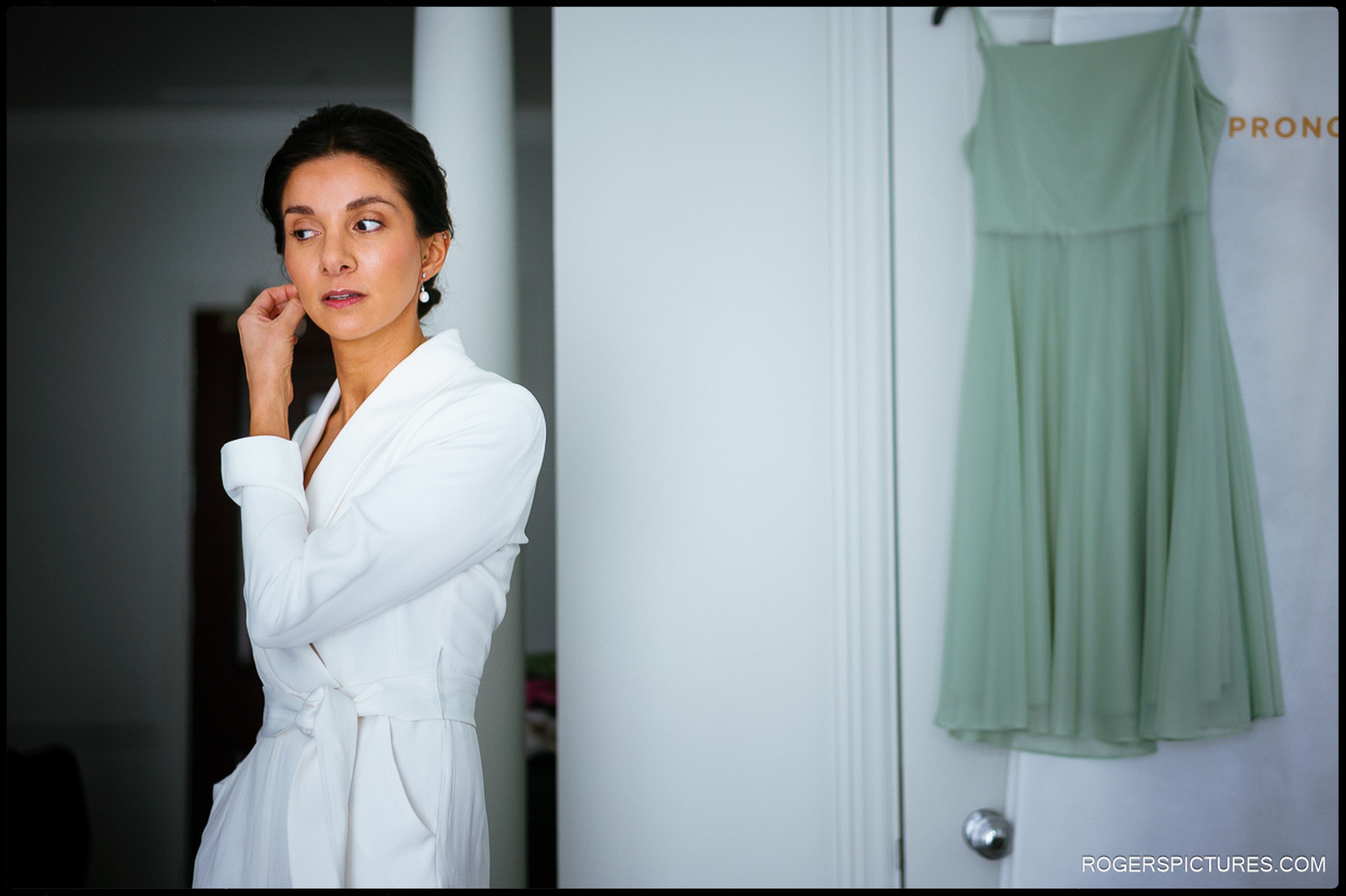 Bride adjusting her earrings before her London wedding at The Langham.