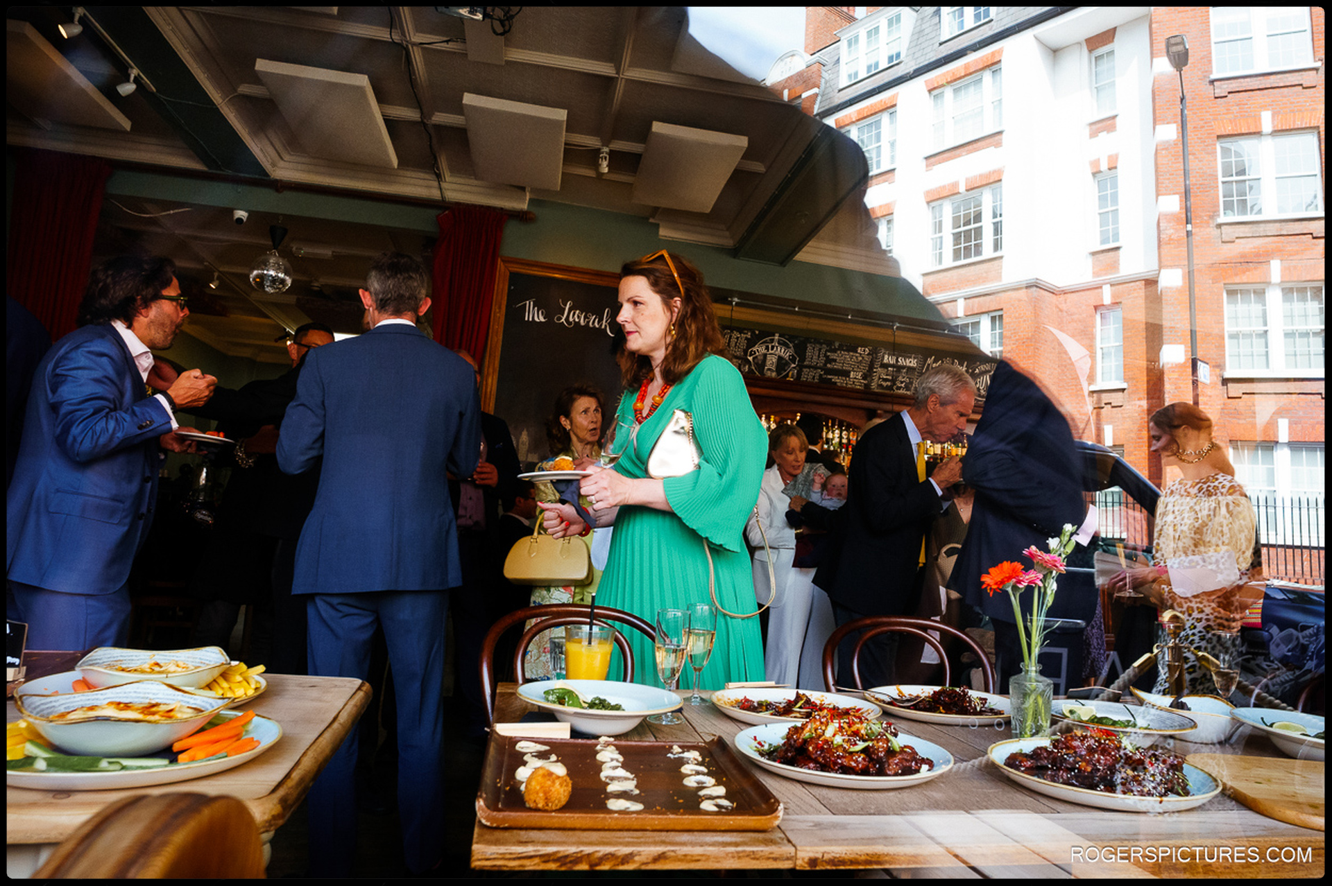 Guests enjoying food and conversation during pre-wedding drinks at The Larrick in London.