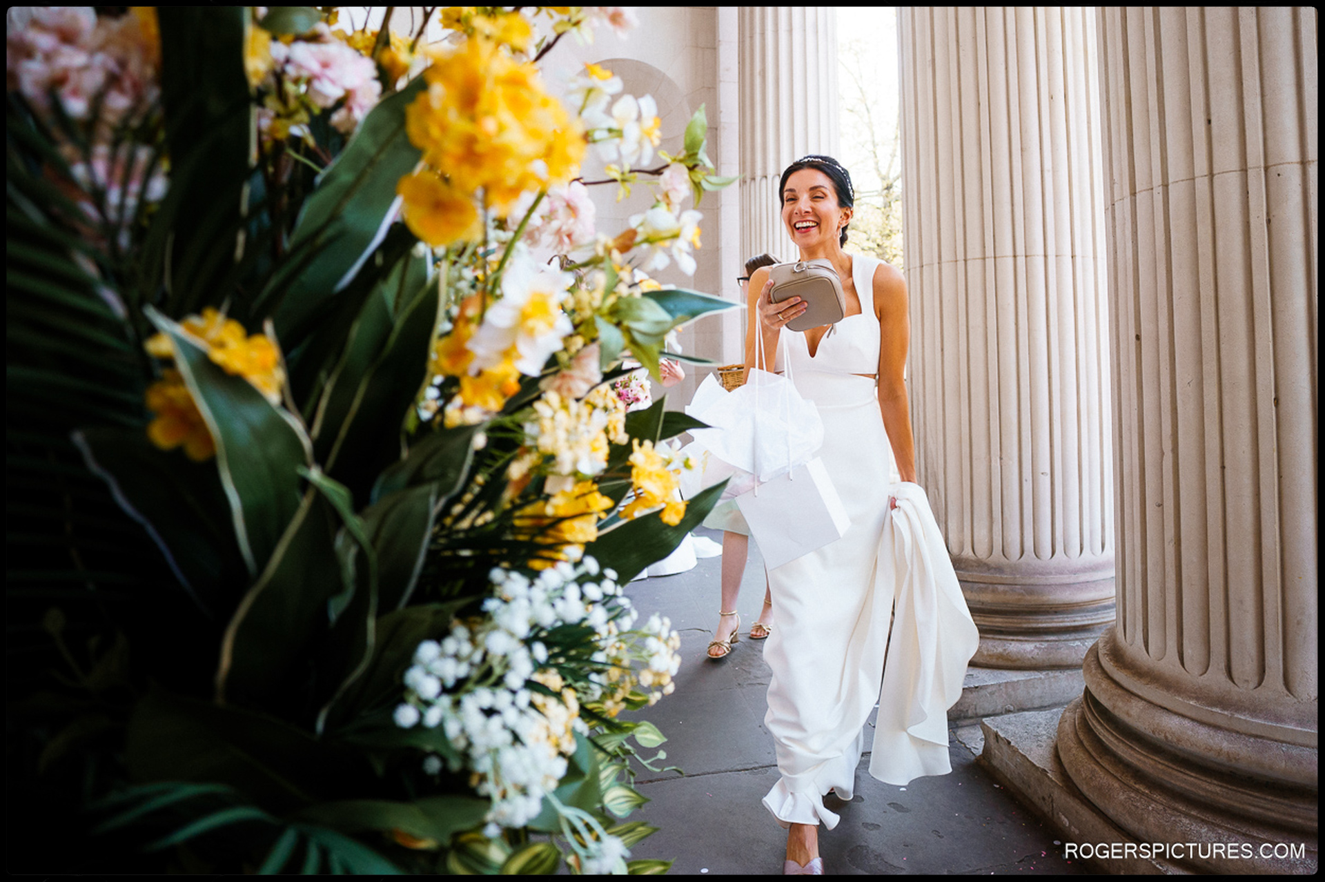 The bride arriving at Marylebone Town Hall, surrounded by vibrant flowers and classic columns.
