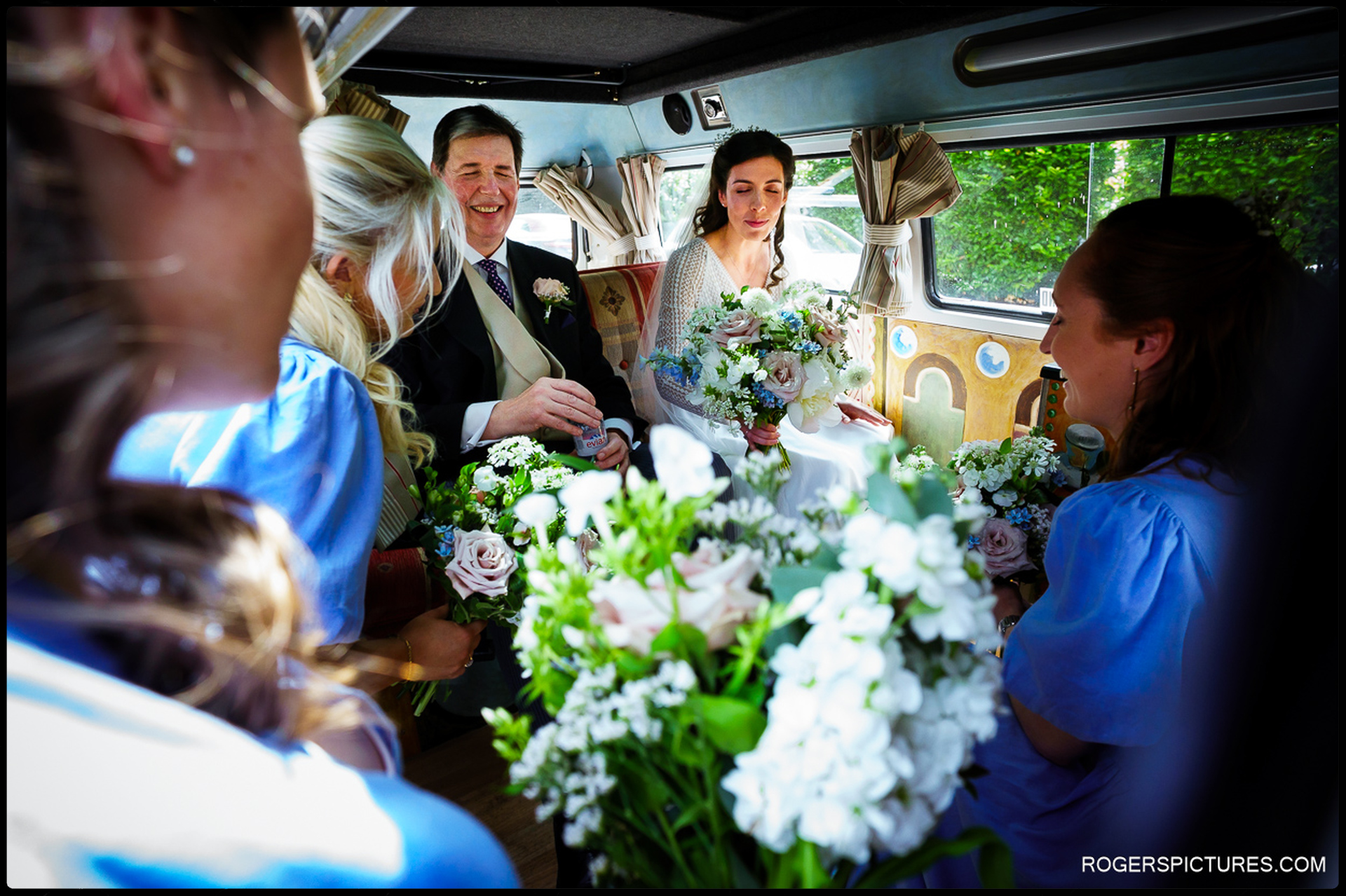 Bride and bridal party inside a camper van filled with flowers en route to the ceremony.