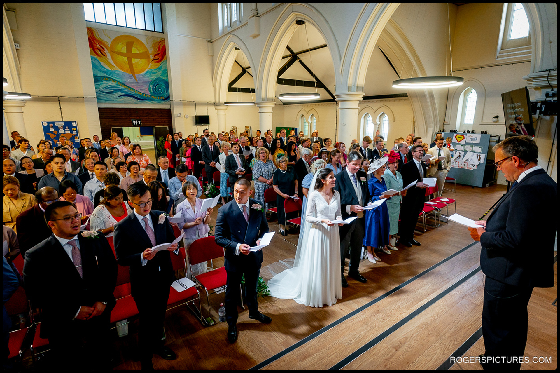 Wide shot of congregation singing during the wedding ceremony at St Peter’s Church.