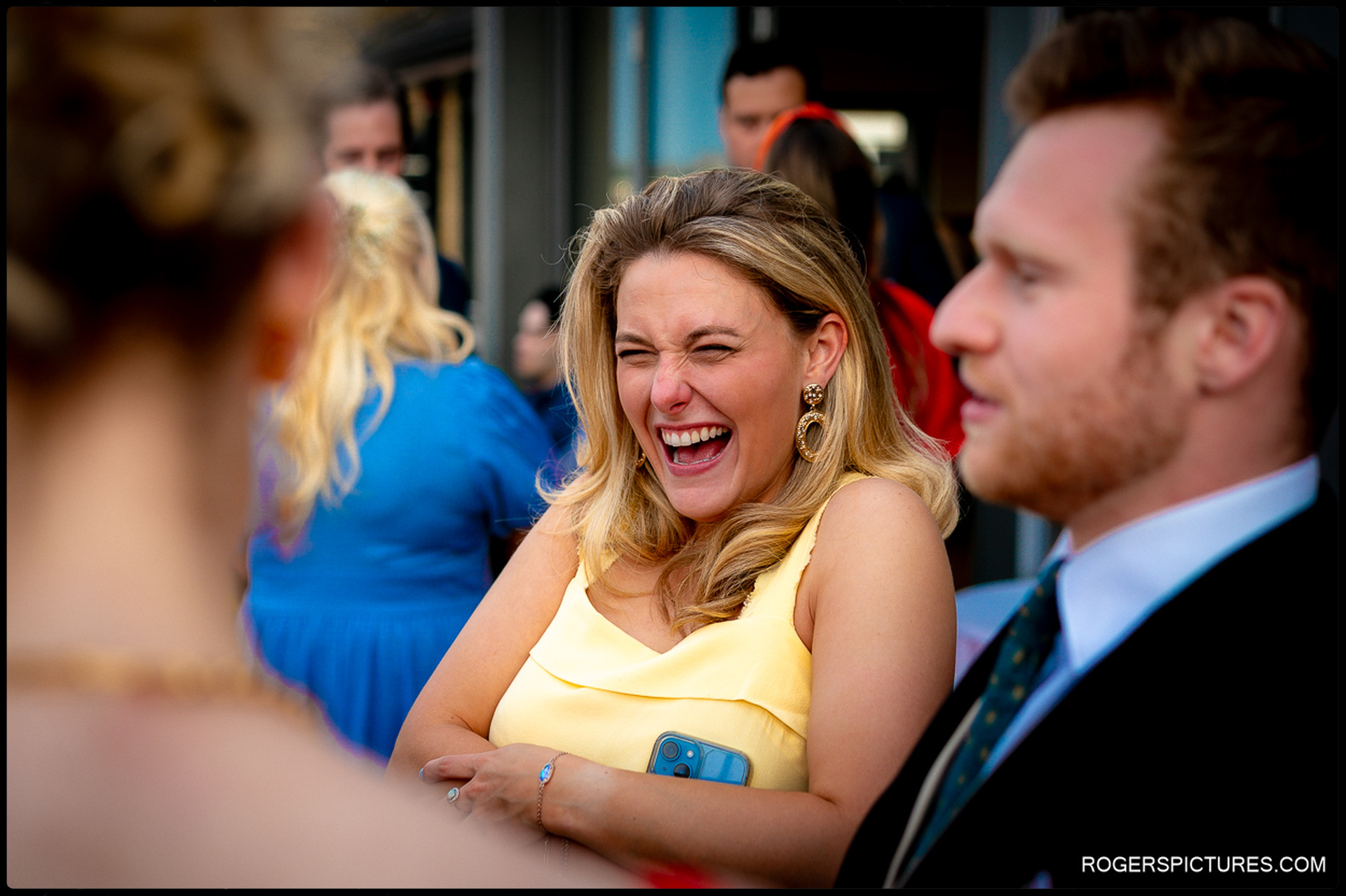 Guest in yellow dress laughing during drinks reception outside Thames Rowing Club.