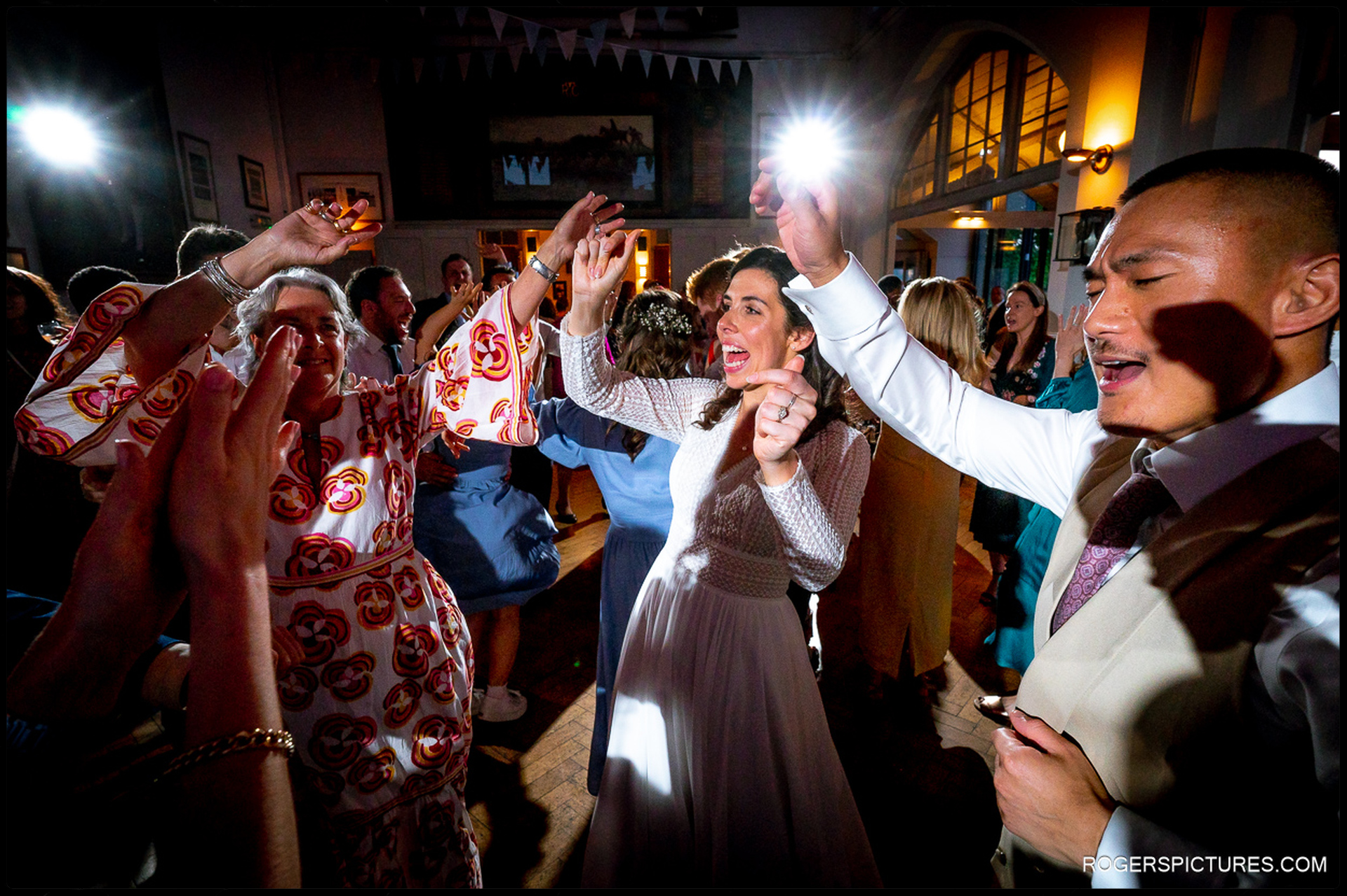 Dancing guests celebrating at the wedding reception inside Thames Rowing Club