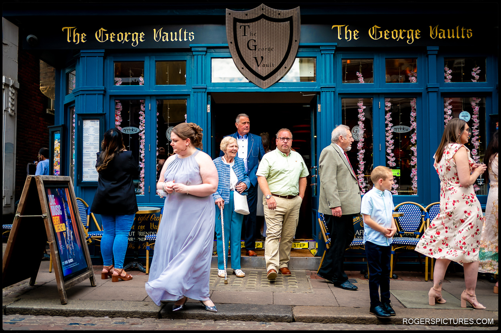 Guests mingle outside The George Vaults bar in Rochester, with bridesmaid and child in the foreground.