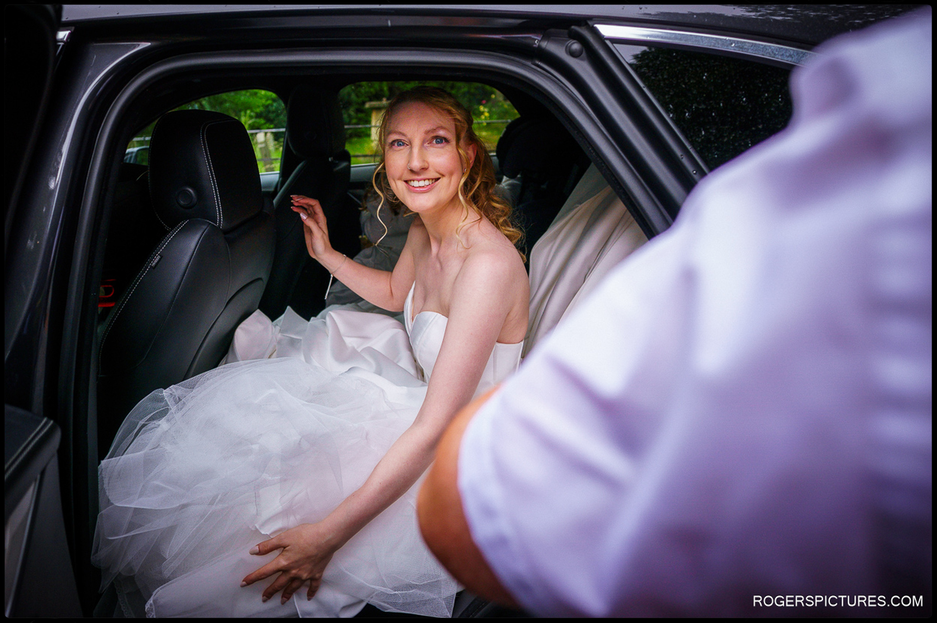 Bride smiling from the backseat of the car en route to St John The Baptist Church, Worcester.