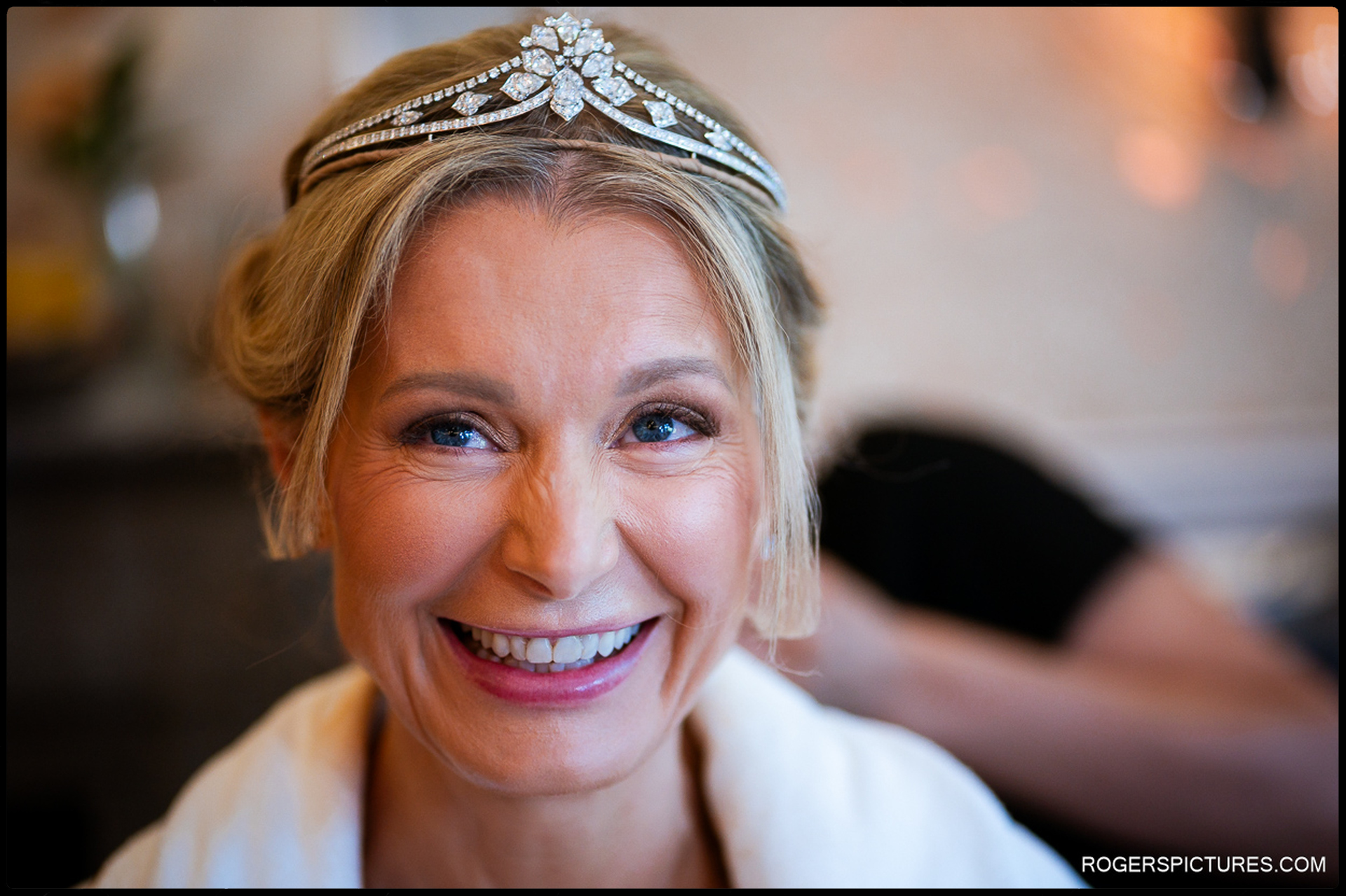 Close-up portrait of the bride smiling, wearing a sparkling tiara and soft natural makeup just before her wedding ceremony.