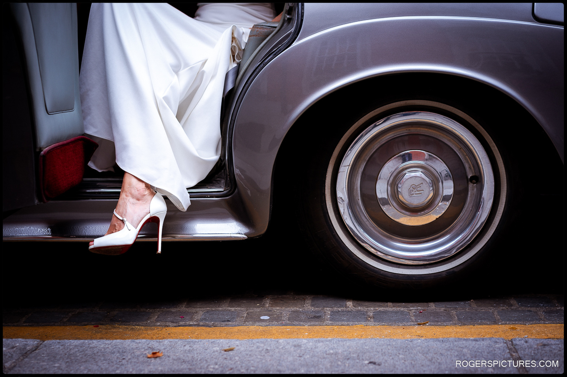 Detail shot of the bride’s shoes and the hem of her dress as she steps out of a classic Rolls-Royce at Chelsea Old Town Hall.