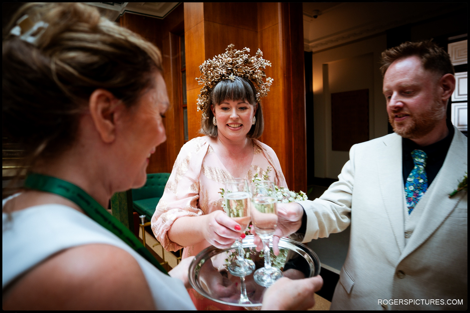 Bride and groom toasting with champagne inside Waltham Forest Town Hall shortly after the ceremony, captured candidly as glasses are handed over.