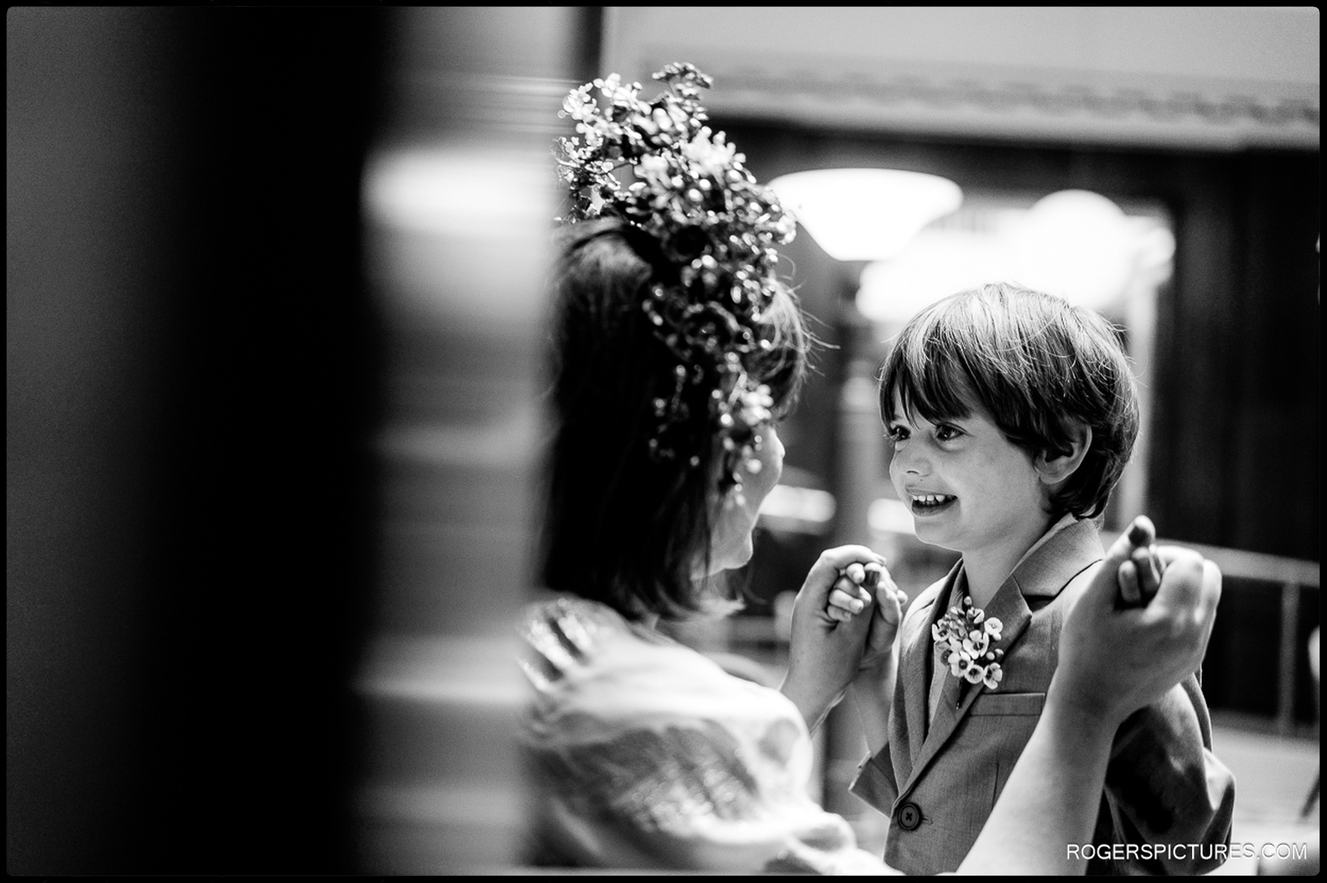 Bride and young child smiling and holding hands inside Waltham Forest Town Hall, captured in a tender black-and-white moment.