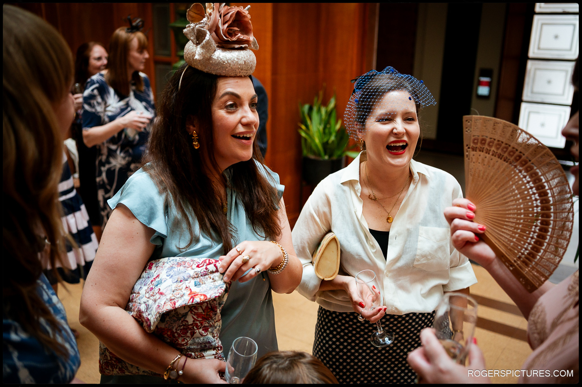Guests laughing and chatting during the drinks reception at Waltham Forest Town Hall, holding glasses and hand fans in a lively candid moment.
