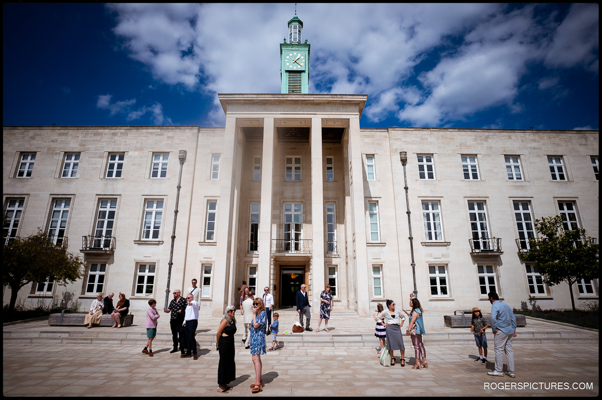 Guests gathered outside Waltham Forest Town Hall in Fellowship Square on a sunny day, chatting and celebrating after the ceremony.