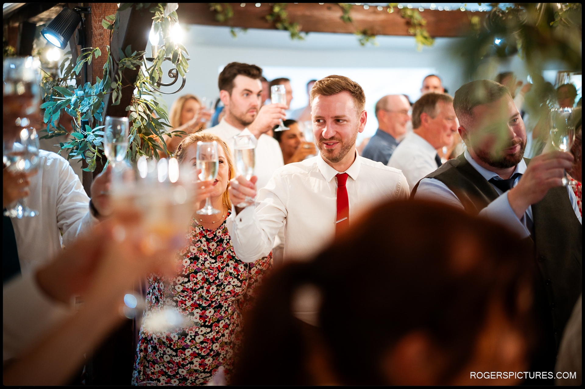 Guests raising champagne glasses during a wedding toast in the reception room.