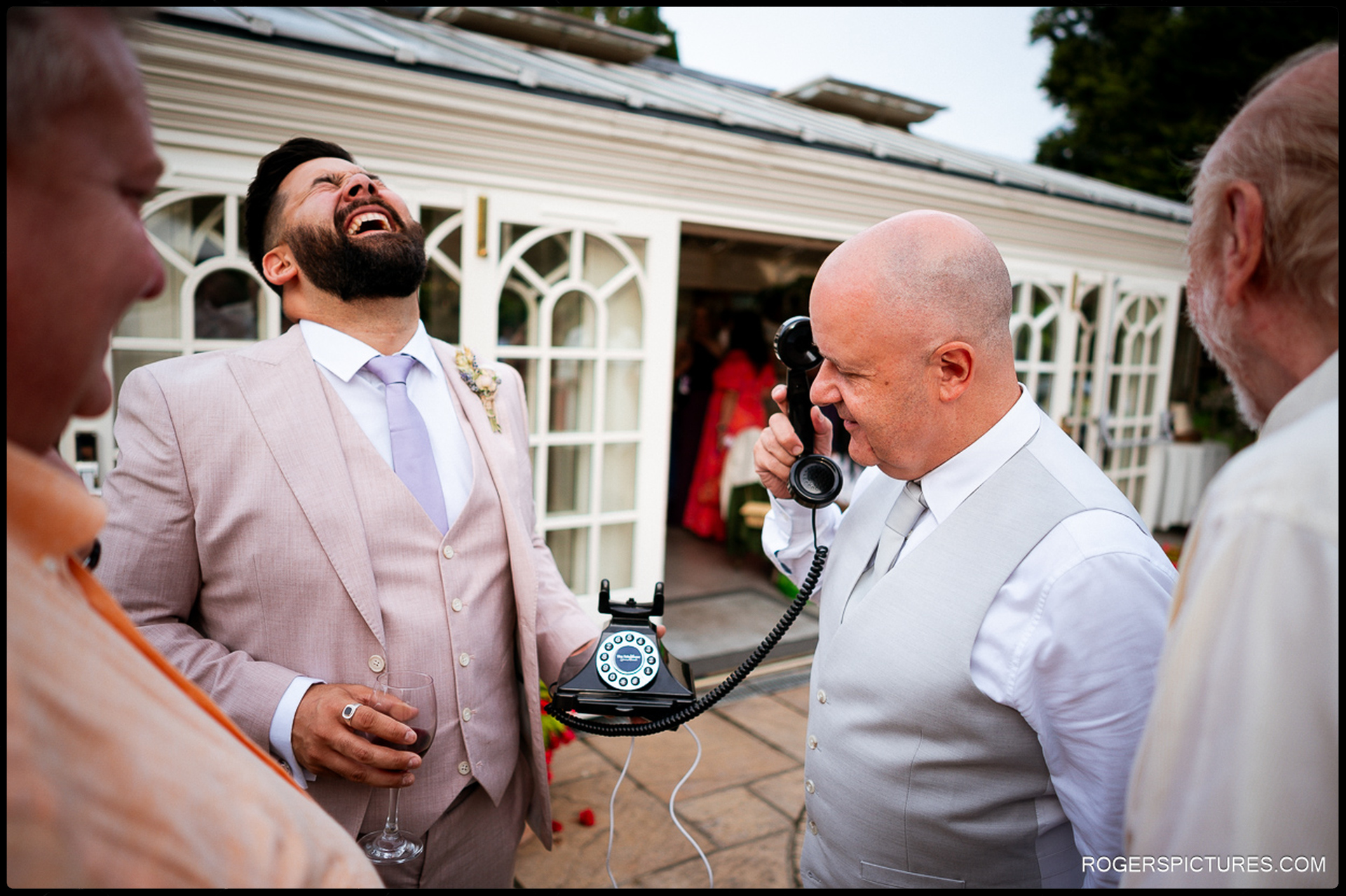 Groom giving a speech at the top table while guests listen and laugh.